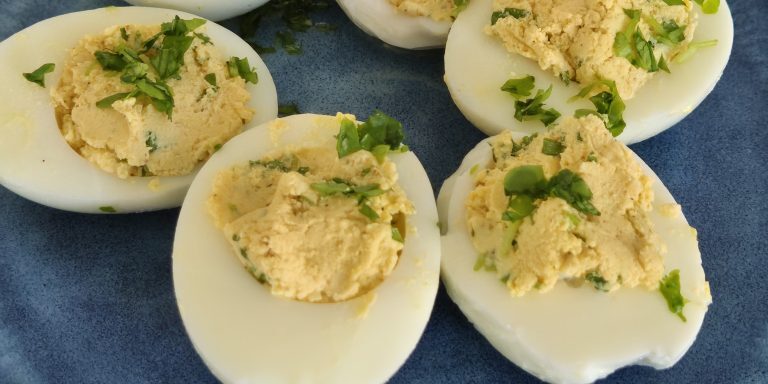 A plate of devilled eggs - boiled eggs halved and thier yolks are mixed with ingredients and spooned back in